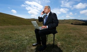 mobile worker - man on his phone and laptop in a field