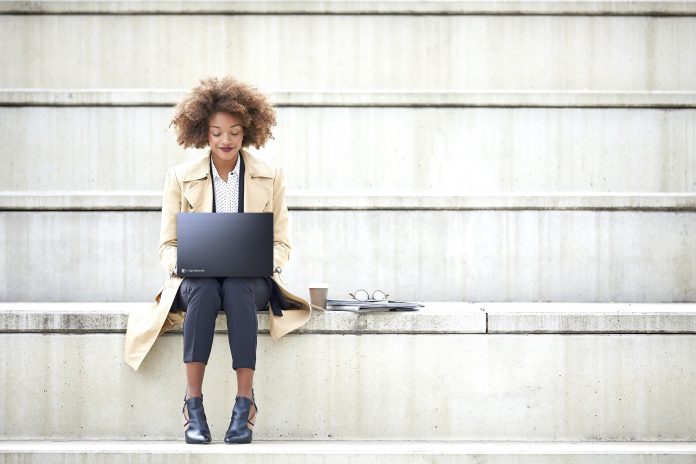 Young businesswoman using laptop on steps